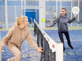 Focused woman and man learning to play padel on tennis court