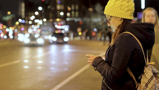 Authentic shot of woman using smart phone in the city at night in London