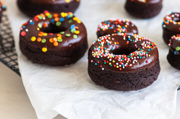 Chocolate baked doughnuts with chocolate frosting and sprinkles.