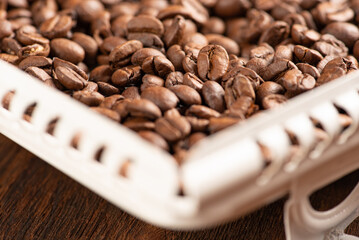 Coffee beans scattered on a white tray on rustic wood, Selective focus