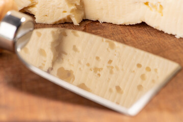 Semi-cured cheese from Brazil arranged on a rustic board on a green and white checkered tablecloth, selective focus.