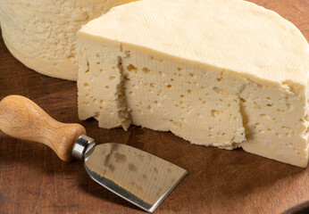Semi-cured cheese from Brazil arranged on a rustic board on a green and white checkered tablecloth,...