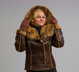 woman posing in a winter jacket with a fur hood on a white background, close-up