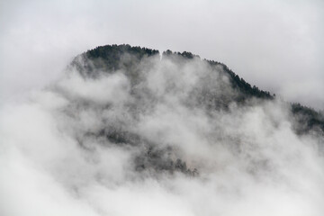 Alpine mountain covered in thick white fog