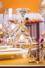 glass cup detail on a table next to white glass plates next to golden knife and fork