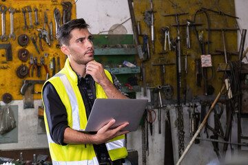 Technical engineer wearing safety vest standing in the factory workplace. Worker holding laptop, touch his chin and looking with equipment tool blur background. Inspection and checking the equipment.