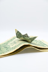 Small money boat on the waves made of dollar bills.