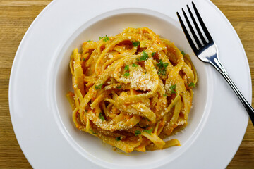 A plate of pumpkin alfredo topped with Parmesan cheese and fresh parsley.