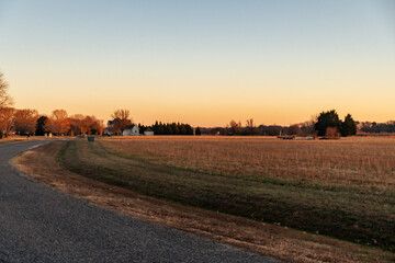 Fototapeta na wymiar Sunset over a farm field in a rural neighborhood