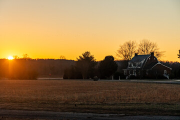 Fototapeta premium Sunset over a farm field in a rural neighborhood