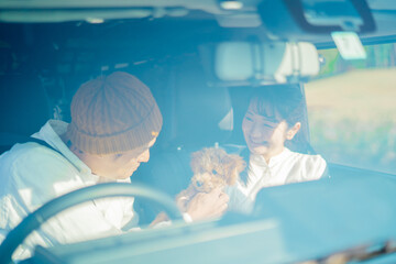 車でお出かけする犬と男女（車内）
