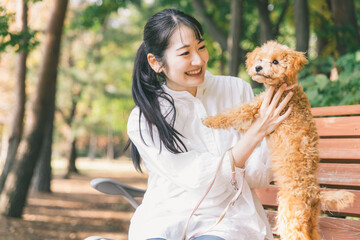 公園で犬と遊ぶ女性（抱く）
