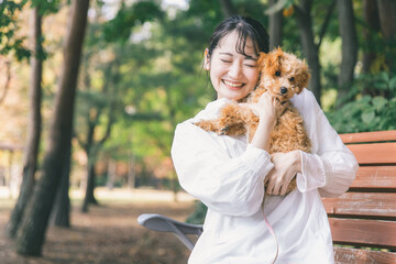 公園で犬と遊ぶ女性（抱く）  © buritora
