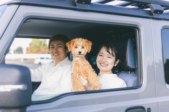 車でお出かけする犬と男女（車内）
