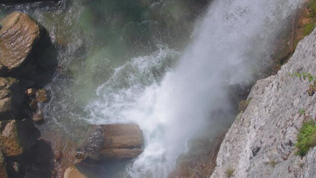 Waterfall crashing into the river. Slow motion, high angle view, arc shot. 