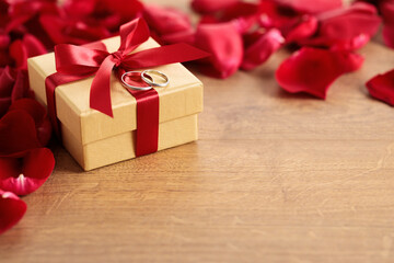 red rose petals and gift box on wooden background. .