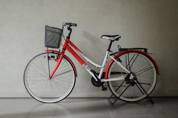 Fototapeta na wymiar Red bicycle with basket in front of gray wall 