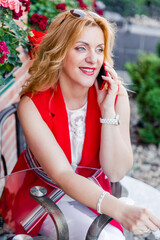 Fototapeta premium Beautiful mature woman businesswoman in white and red suit talking on the phone