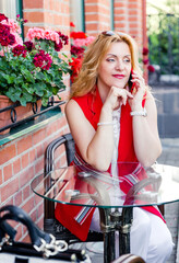 Beautiful mature woman businesswoman in white and red suit talking on the phone