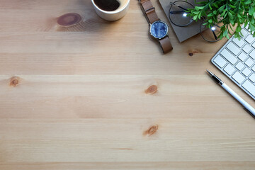 Above view wristwatch, coffee cup, notebook, houseplant and keyboard on wooden background.