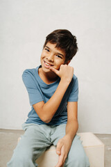 Confident indian boy sitting on a wooden box, making a gesture