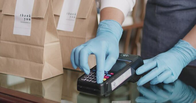 Close-up hand asia woman people work in small sme coffee cafe shop store owner use cashless wifi paywave nfc scan app smart pos reader sale in take out food drink order in urban city life contactless.