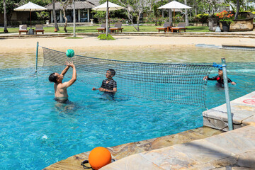 Play with family. Play volleyball in the pool. vacation with family. Father and son game