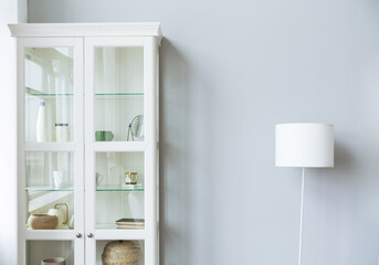 White cabinet and lamp stand near gray wall