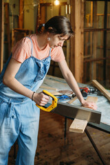 Woman working with wood in workshop. Measuring plunk, drilling holes, sewing wood. Reuse, reduce, recycle old things. Aware consumption and gender equality. Tools to repair, closeup