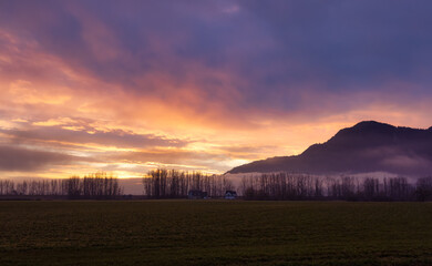 Farm lands and Canadian Mountain Nature Landscape. Dramatic Winter Sunset. Located near Chilliwack and Abbotsford, British Columbia, Canada.