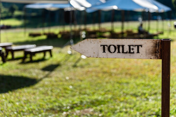 Old vintage metal toilet outdoor sign in public garden at summer day.