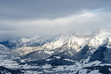 Fototapeta na wymiar Snow capped mountains under a blanket of clouds and the view of Maria Alm am Steinernen Meer - Hochkönig region - Salzburg, Austria