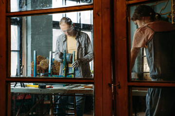 Fototapeta premium Man and woman working in workshop, doing furniture, reuse old materials to new product. awareness in consumption. Small family business. Recycling, sustainability refurbishments maintenance for home