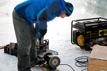 Worker sharpens a chisel on the emery wheel