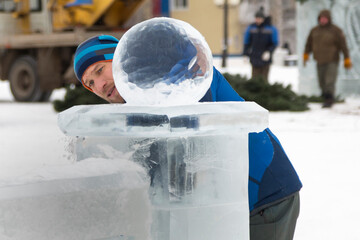 Portrait of a sculptor in a blue winter suit with a chisel in his hands at work