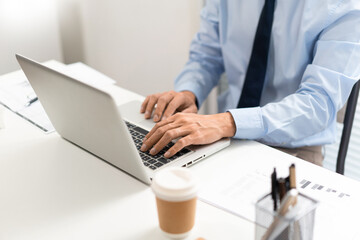 Working Man Conept The man in blue shirt with navy necktie sitting at his desk and typing letters on his notebook