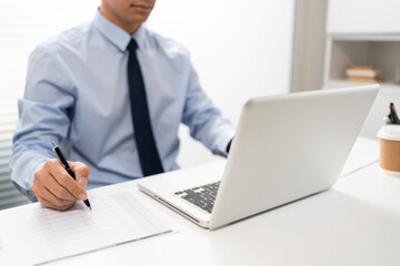 Working Man Conept The male officer sitting in the office, laying his left hand on the laptop, and...