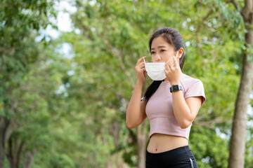 Fototapeta premium Asian woman wearing face mask while she running in public park after coronavirus outbreak and city lockdown a new normal life.