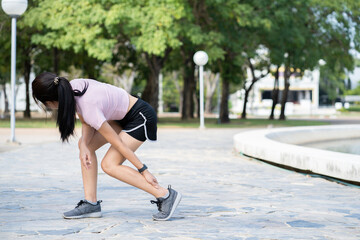 Asian woman runner holding his sports leg injury, muscle painful during training. Asian runner having calf ache and problem after running and exercise outside.