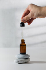 A woman's hand holds a pipette and drips skin serum into a glass dropper. Care cosmetics.