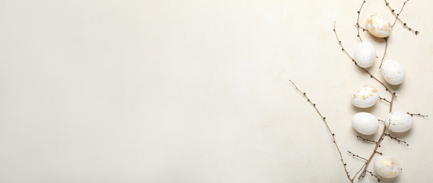 Beautiful Easter eggs and tree branches on light background with space for text