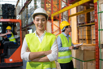 Portrait of Asian warehouse woman worker smile with arms crossed, Colleagues working and checking parcel box. export import or logistics service business. employee and labor factory