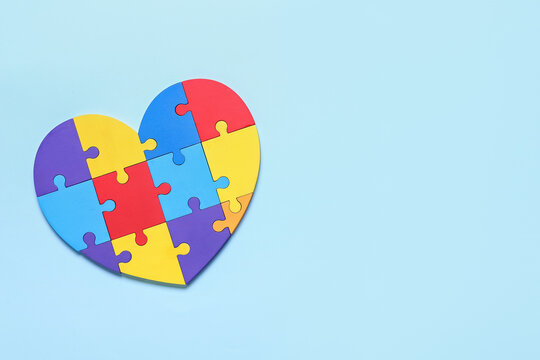 Colorful puzzle pieces in shape of heart on color background. Concept of autistic disorder
