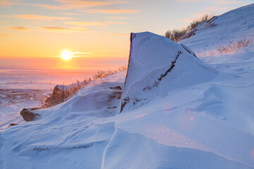 Winter arctic landscape. The view from the snow-covered mountainside to the sunrise over the frozen...