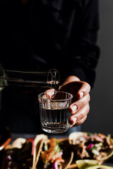 Barman hands serving mexican mezcal shot in a traditional glass with tacos and food at background in Mexico
