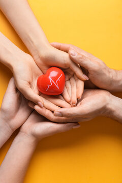 People holding red heart with cardiogram drawing on color background, closeup. Donation concept
