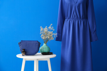 Table with female accessories and elegant dress near color wall