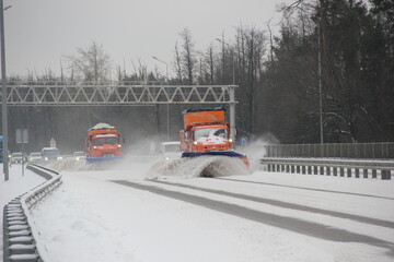 Snow plow trucks work on a highway to remove snow after the heavy snowfall