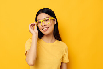 Fototapeta premium pretty brunette in glasses gesturing with hands copy-space yellow background unaltered