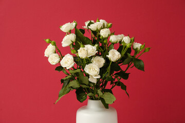 Vase with bouquet of beautiful roses on red background, closeup